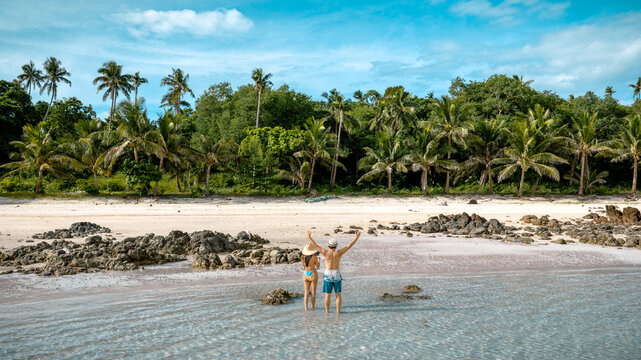 Couple tourist stay happy moment at the edge of the sea beach under shallow of the crystal clear water in summer trip on tropical island island