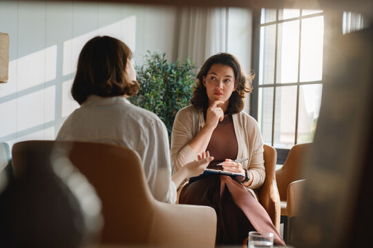 Professional Therapist Listening to Client in Private Counseling Session, Natural Light Office