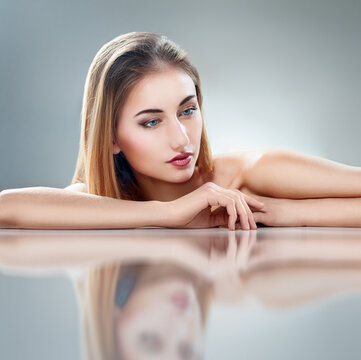 Elegant Woman with Natural Makeup Reflected on Glossy Surface