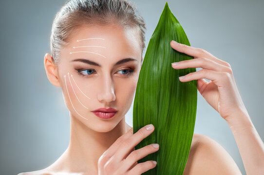 Beautiful Woman with Clear Skin and Green Leaf ? Natural Skincare and Beauty Concept