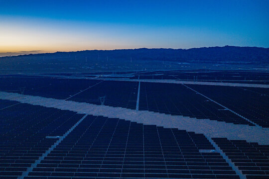 Solar photovoltaic panels at sunrise/sunset; wind turbine power plant; new energy