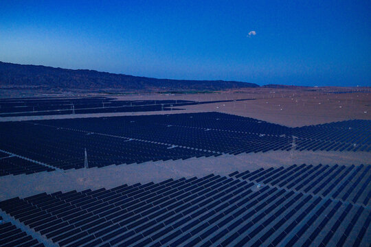Solar photovoltaic panels at sunrise/sunset; wind turbine power plant; new energy