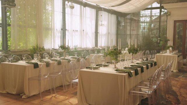 Wedding reception hall with decorated tables, floral centerpieces and seating prepared for guests.
