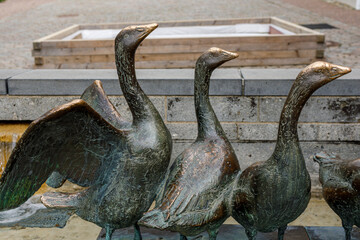 Close-up of weathered bronze geese statues, one with wings spread, part of a public art installation © vegefox.com