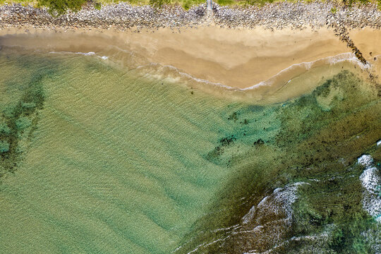 Aerial downward view of ocean waves crashing over the rugged rocky coastline at Brooms Head, capturing white surf, exposed rock formations and surrounding Pacific Ocean along the Clarence Valley coast