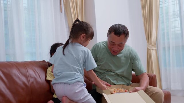 Grandfather eats pizza and cake back to his granddaughter on the sofa in the living room.