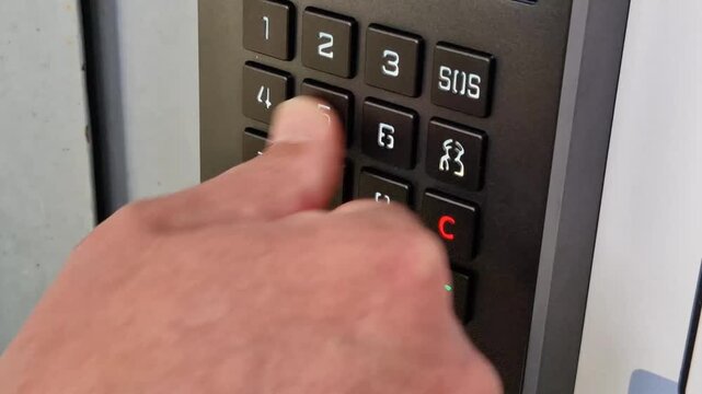 Hand pressing button on smart intercom keypad for entry access