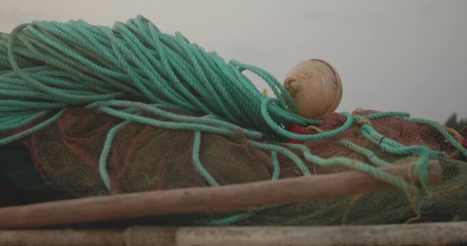 Green fishing ropes and net piled on wooden boat deck at harbor.