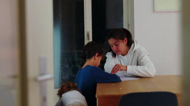 Frustrated mother corrects her son during evening homework at the home table, balancing emotional strain, firm discipline and continued educational support