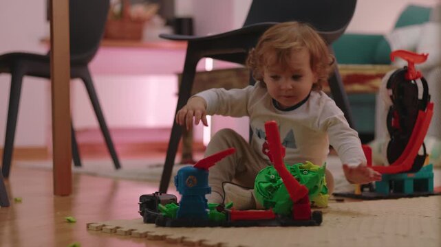 Toddler operates a colorful action playset on the living room floor at home, exploring moving parts while developing curiosity, coordination and independent play skills