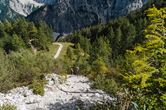 Distant people hiking in wide rocky mountain valley. Happy family travel concept and healthy outdoor active lifestyle.