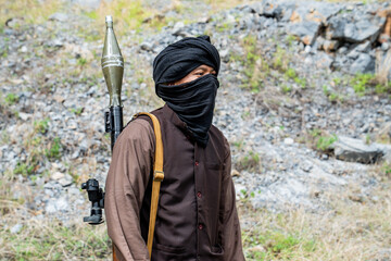 Naklejka premium Man stands in a rocky area while carrying a weapon and wearing a mask during the daytime