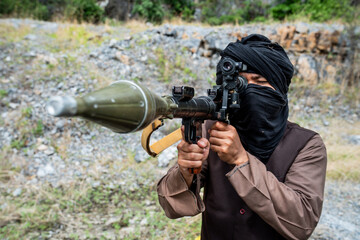 Naklejka premium Person holding a rocket launcher in a rocky outdoor area under daylight conditions
