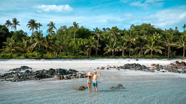 Couple tourist stay happy moment at the edge of the sea beach under shallow of the crystal clear water in summer trip on tropical island island