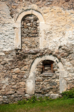 Vusanje, Gusinje Municipality, Montenegro - 28 July 2005: View of an old stone wall with two arched niches, one filled with stones and one with a wooden shutter.