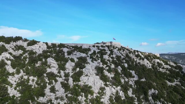 Aerial drone video over Ston, Croatia, on Pelje&scaron;ac Peninsula, showcasing historic Ston fortifications, rugged limestone hills, blue Adriatic bays, and shellfish farming areas of Mali Ston Bay