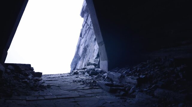 Wide internal view toward bright triangular opening, layered rubble and concrete strata like archaeological dig, textures and sediment layers highlighted