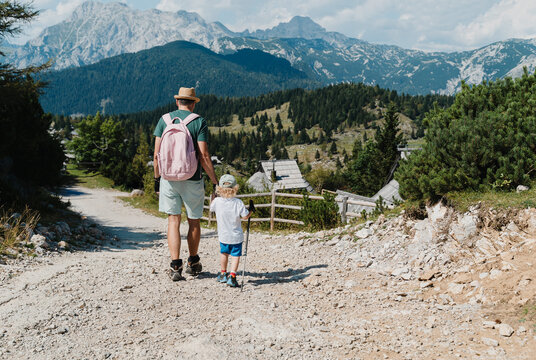 Father and young son walking down a rocky mountain trail enjoying an active family vacation.
