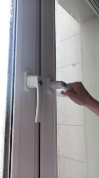 Hand locking white plastic window with key. Sliding doors, white handles, glass panels, indoor view.