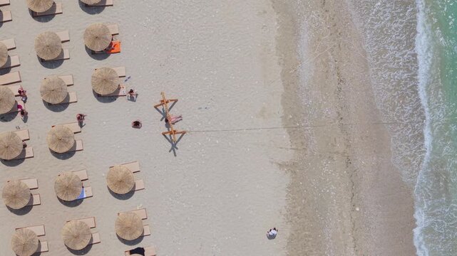 Vlore County, Albania - 12 August 2026: Aerial view of Kroreza Beach with rows of straw umbrellas on the sand and turquoise sea waves along the shoreline.