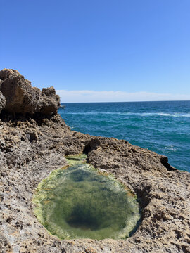 Natural tidal pool in rocky coastline with turquoise ocean