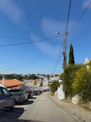 Naklejka premium Hillside street with parked cars in Portuguese coastal town