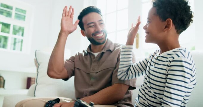 Dad, child and playing video game with high five in home for winning or fair match together. Father, kid or smile with controller for fun competition, bonding or entertainment on couch in house