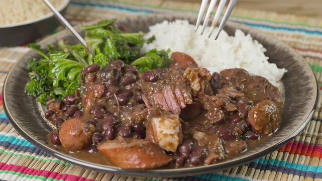 Pulling tender beef apart while eating feijoada. A complete Brazilian feast including rice and kale.