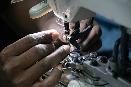 Dhaka, Bangladesh - 26 August 2026: View of a worker using a sewing machine in a ready made garments manufacturing factory with precise hand movements and industrial equipment.