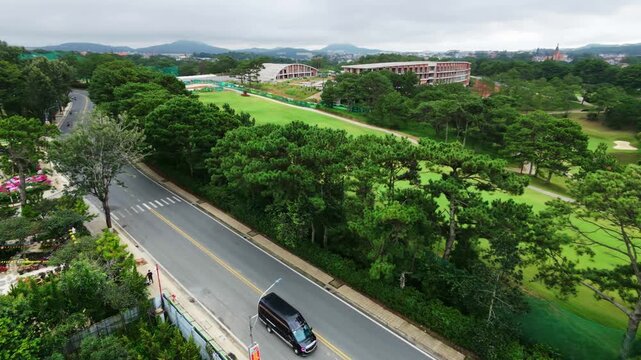 Aerial view of car driving through lush landscape on cloudy day
