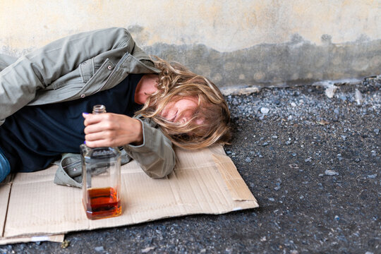 Person sleeping outdoors with bottle.