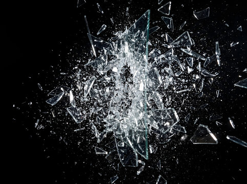 Shattered glass fragments exploding outward against dark background