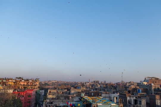 Lahore, Punjab, Pakistan - 07 February 2026: View of the Basant festival with colorful kites filling the clear blue sky above the crowded rooftops of the old city.
