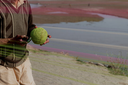 Lahore, Pakistan - 07 February 2026: View of a man holding a ball of green kite string in preparation for the Basant festival.