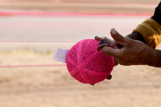 Lahore, Pakistan - 07 February 2026: View of a person holding a large ball of bright pink kite string used during the Basant festival.