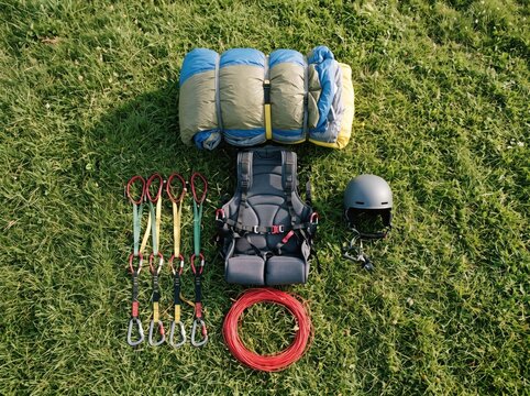 Paragliding Equipment Laid Out: A complete set of paragliding gear, including harness, helmet, lines, and packed parachute, is neatly arranged on a grassy field, ready for an adventure in the sky.
