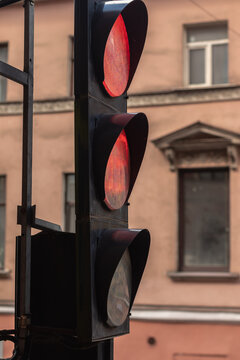 Side view of a red traffic light against the background of a yellow building wall in the city, close-up.