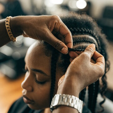 Close up african hairstylist braided hair of afro american female client in the barber salon. Black healthy hair culture and Style. Stylish therapy professional care concept. Selective focus.
