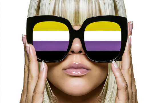 Blonde woman holding oversized black sunglasses with nonbinary pride colors in lenses on white background.