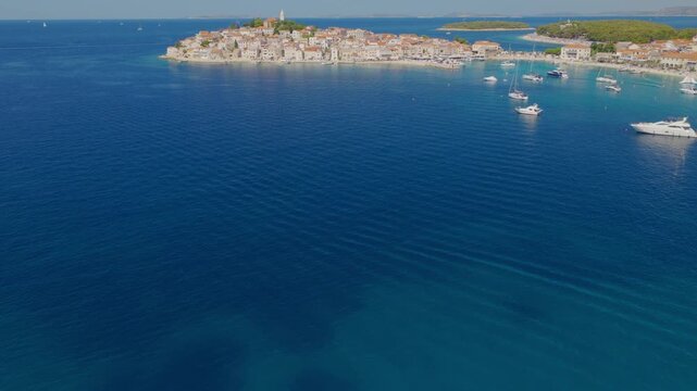 Aerial drone flight over the turquoise Adriatic coastline of Primo&scaron;ten, Croatia, with smooth upward and forward movement revealing rocky shores, coastal homes, clear water and Mediterranean landscape