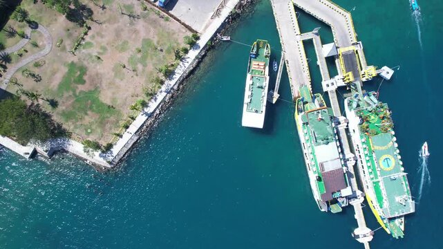 Top down aerial drone footage of passenger ferries docked at a waterfront ferry terminal in Labuan Bajo, Flores, Indonesia.