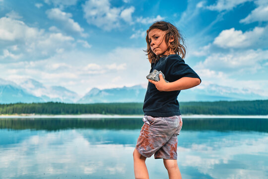 Boy holding a rock at a turquoise mountain lake