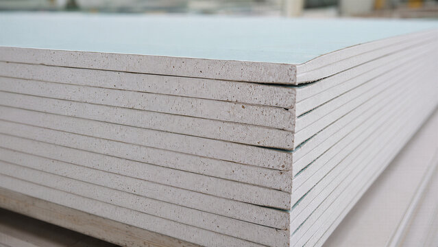 Stack of drywall sheets at factory warehouse. Plasterboard production and building material manufacturing concept. Gypsum board for construction and interior renovation industry