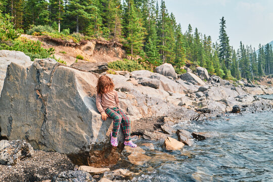 Boy leaning against a boulder on a rocky mountain lakeshore