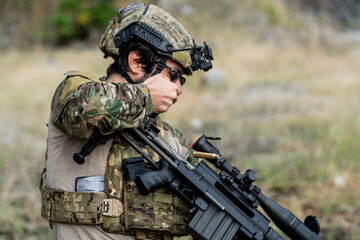 Fototapeta premium Soldier prepares weapon at training site in outdoor setting during daytime hours
