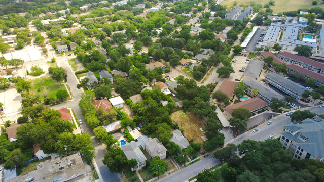 Quiet neighborhood avenues crisscross Mahncke Park near Broadway corridor. Mature shade trees conceal detached family cottages, swimming pools, paved roadways, San Antonio, Texas