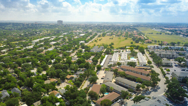 Mahncke Park residences sit beside apartment complexes near Broadway. Sprawling tree canopy shields low rise homes, expansive green spaces, connected surface parking zones, San Antonio, Texas