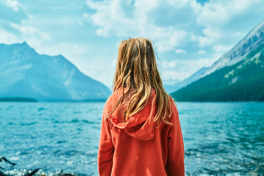 Boy standing beside a turquoise mountain lake