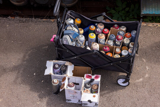 Vilnius, Lithuania - 08 August 2026: View of a black cart filled with various spray paint cans and cardboard boxes used by artists at the Meeting of Styles street art festival.
