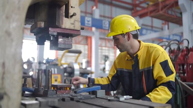 Industrial engineer in protective workwear and helmet operating a metal press machine during factory production, quality control, and manufacturing inspection.